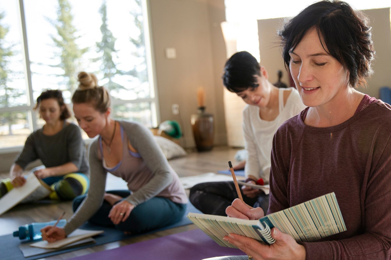 Women with journals taking notes at restorative yoga retreat
